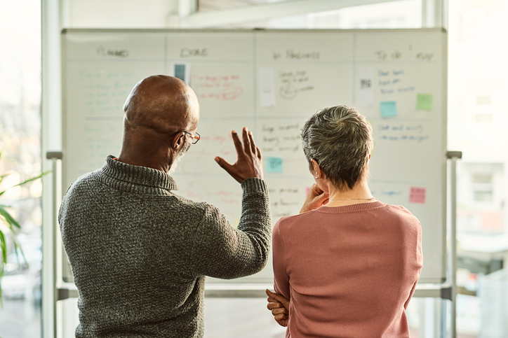 Stock photo of two people in front of a whiteboard